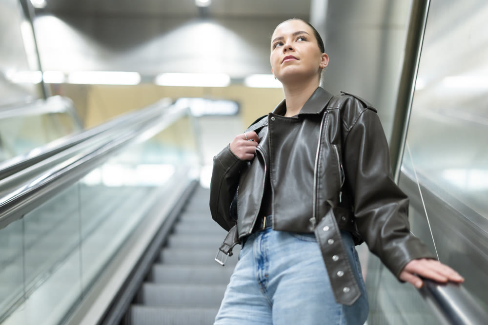 Young woman riding escalator up in subway station