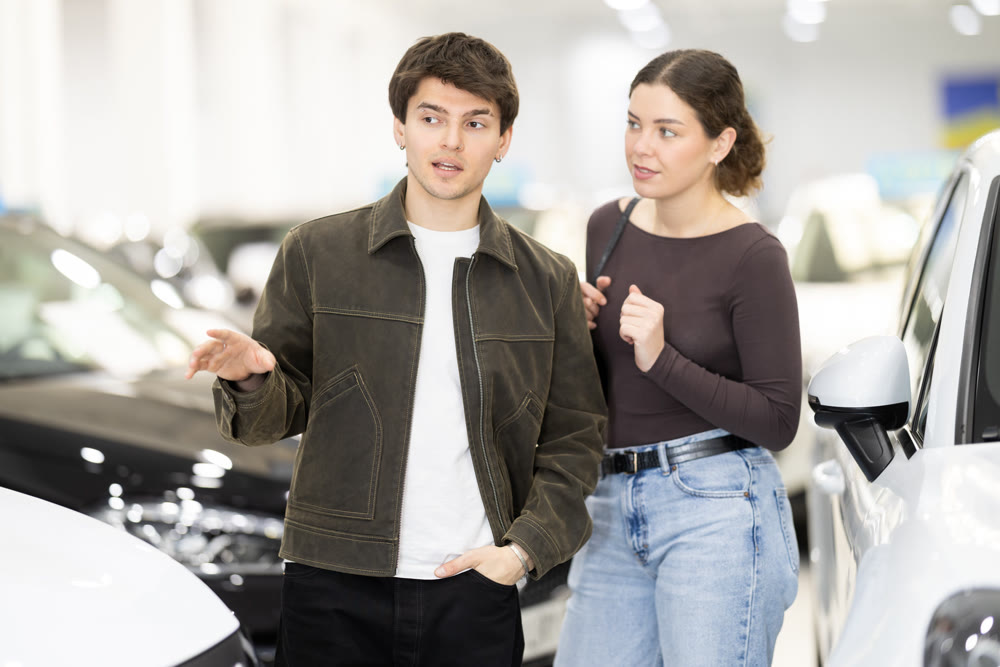 Young couple choosing car at auto dealership