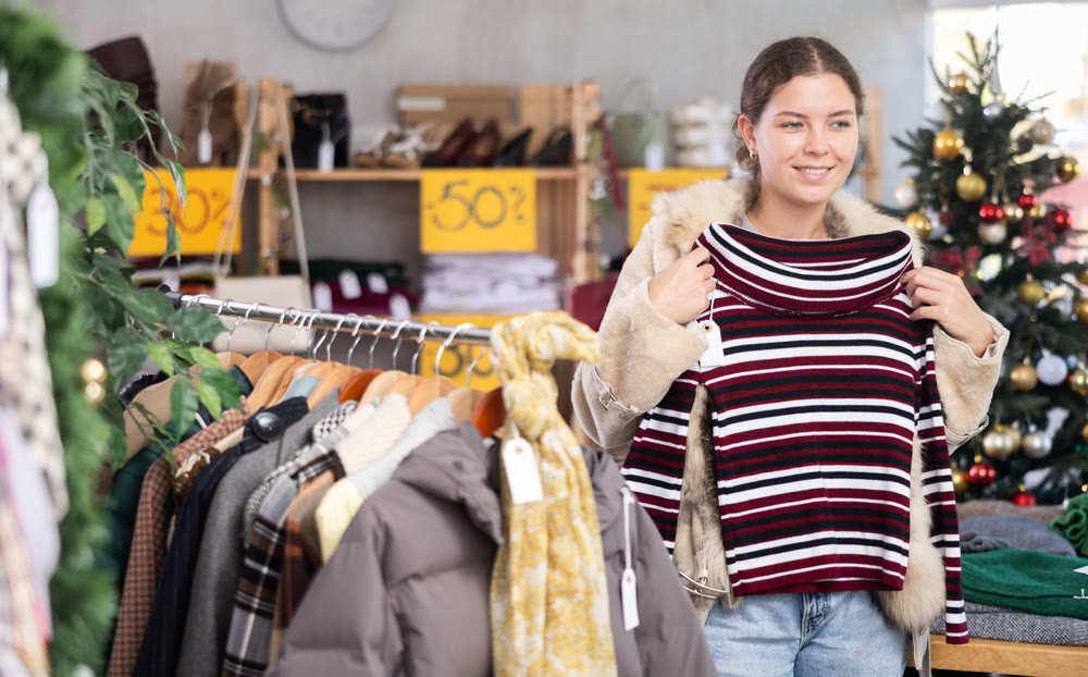 European girl near showcase pick out and buying sweater, New Year eve