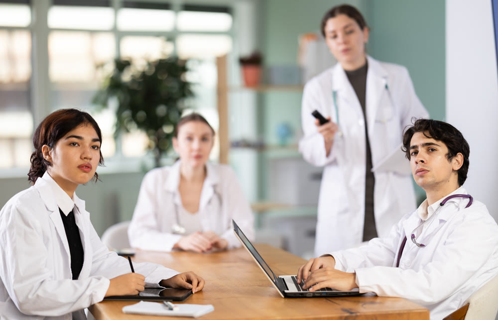 Interested medic student or doctor sitting at table discussing ideas and watching presentation during meeting in office