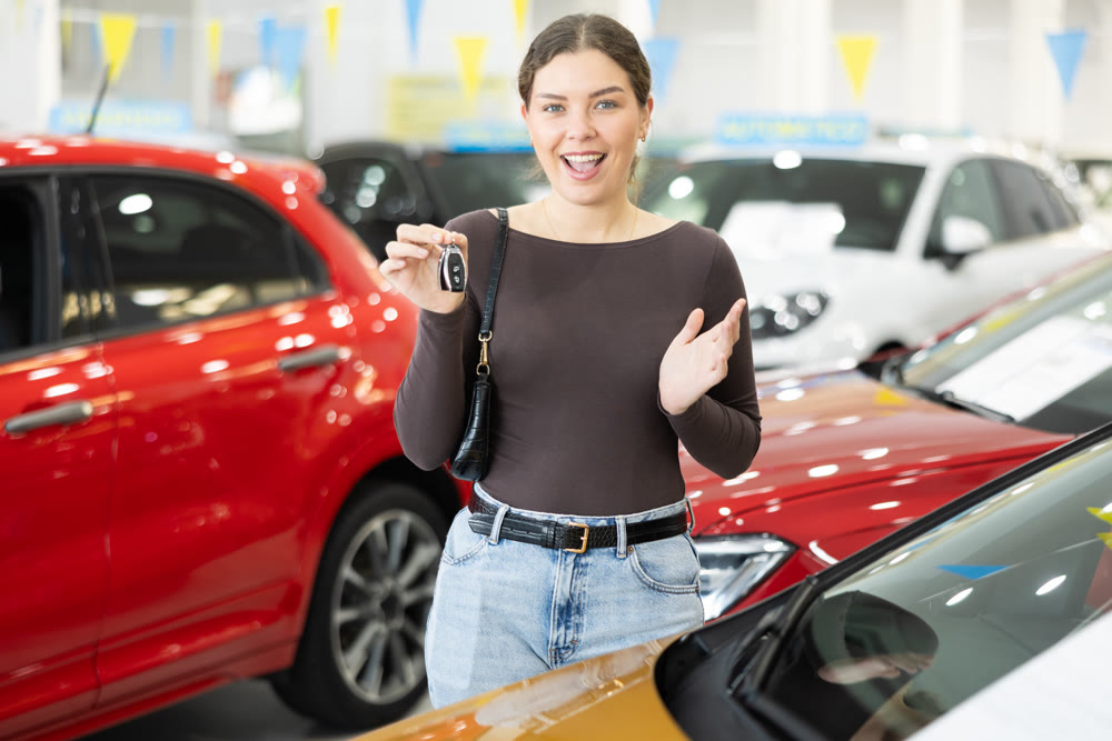 Young woman is happy to buy a car, she keeps the keys