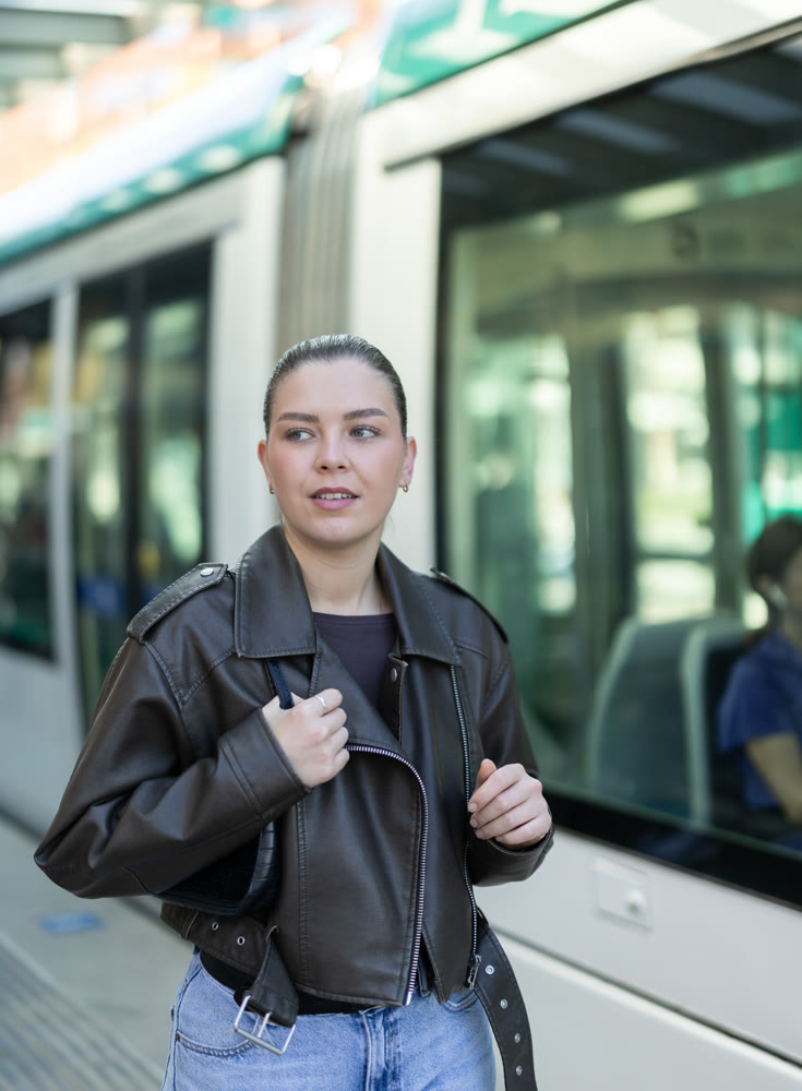 Young woman waiting for tram at public transport stop