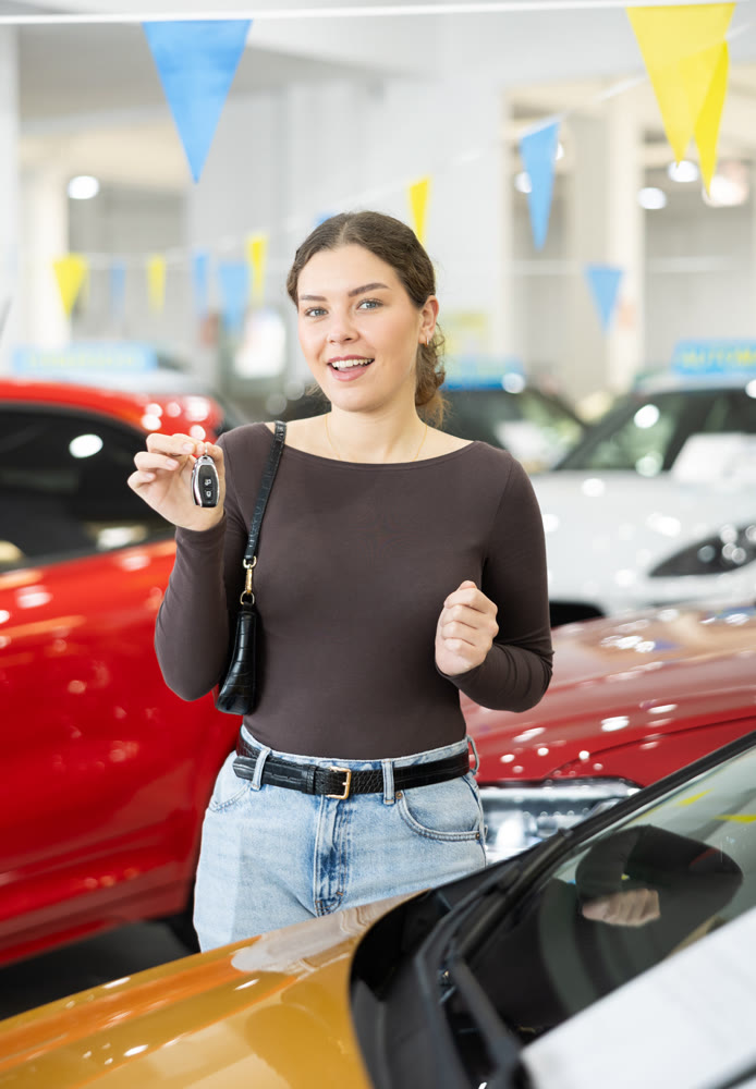 Happy cheerful girl bought car - portrait of joyful girl with car keys in car dealership