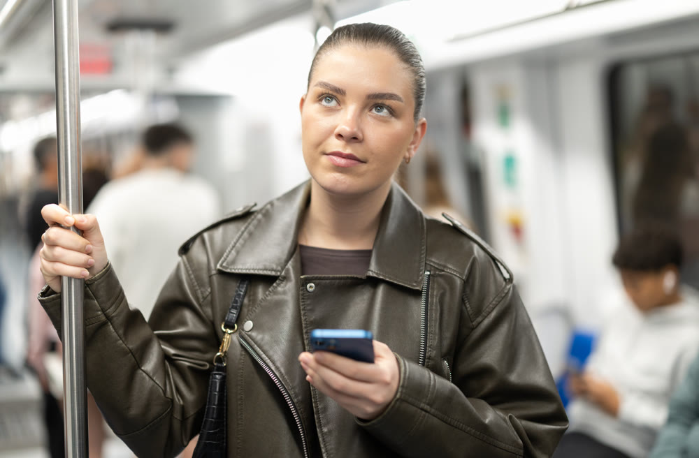 Girl stands in subway car and writes message on her smartphone screen
