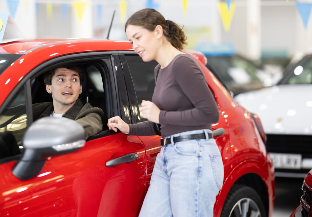 Young couple choosing car at auto dealership
