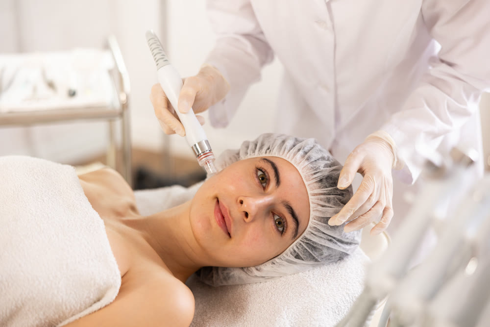 Young woman getting cosmetic facial procedure using ion bubble pen