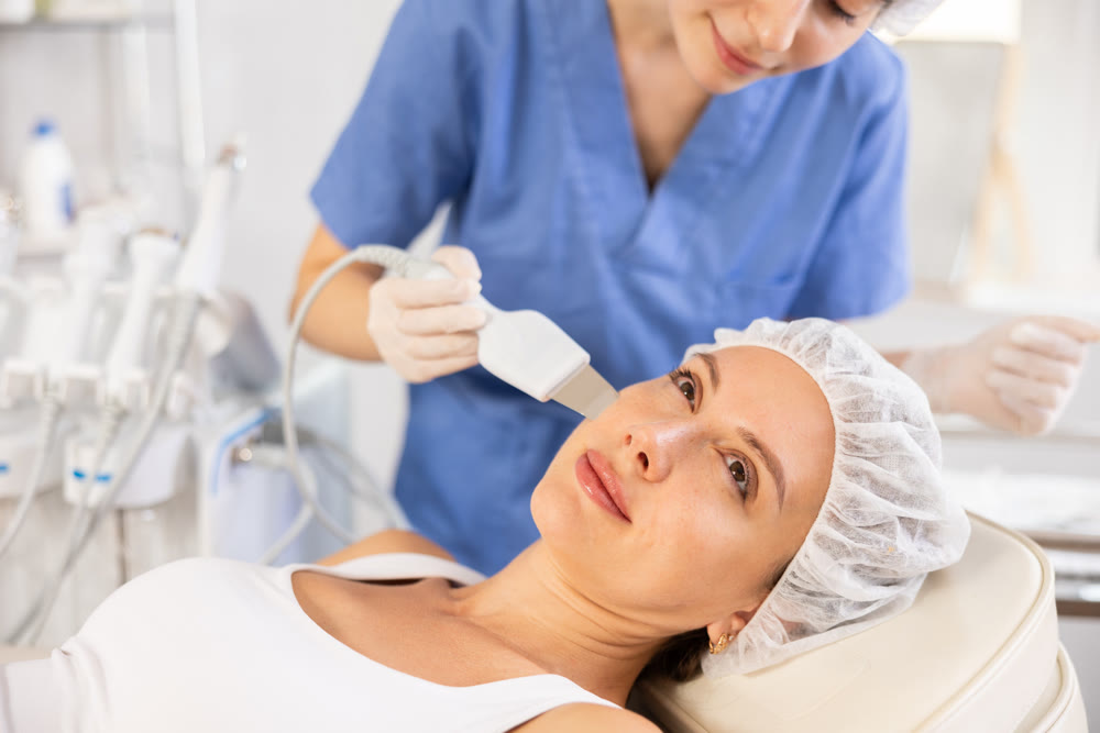 Young woman undergoing facial cleansing procedure using ultrasonic shovel