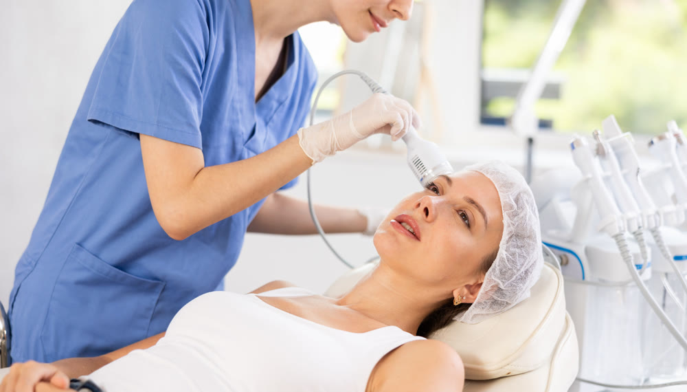 Young woman cosmetologist doing whitening procedure to young woman