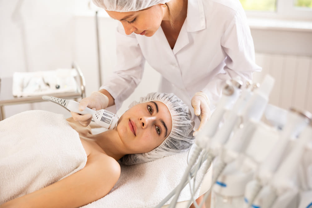 Young woman cosmetologist doing whitening procedure to young woman