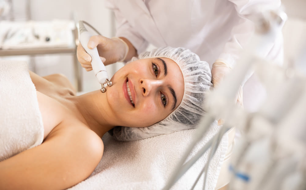 Female client getting face skin rf lifting procedure in cosmetic clinic