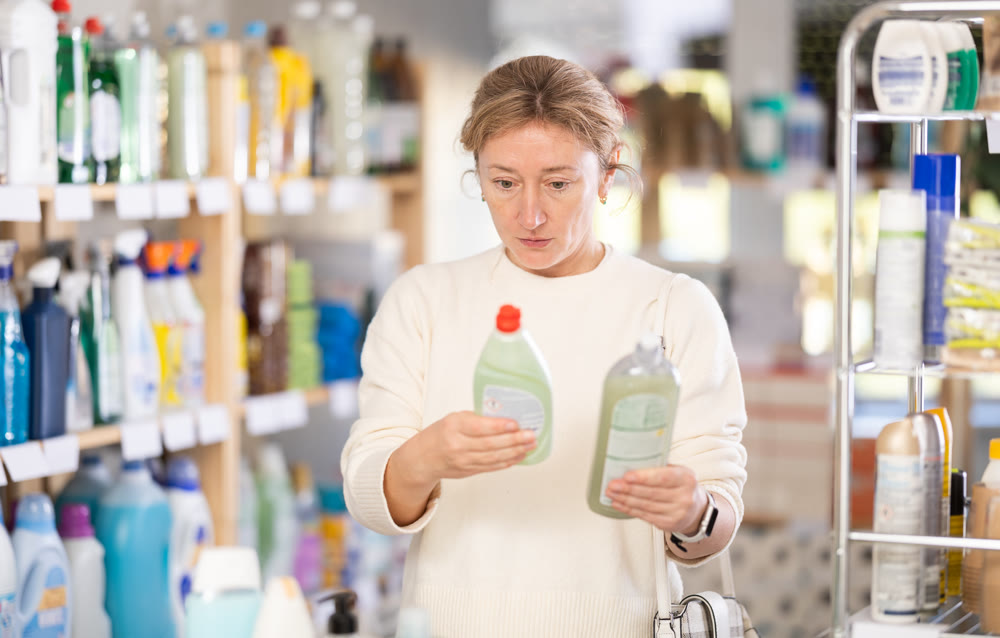 Woman customer diligently choosing out dishwashing liquid