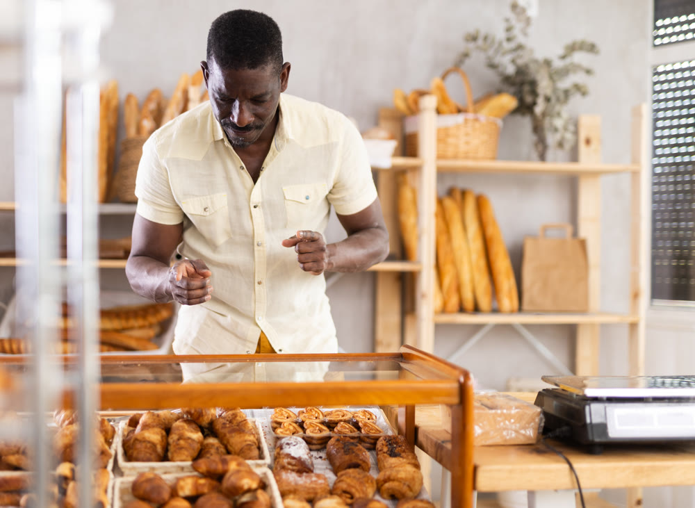 African man near window of bakery food court store examines assortment