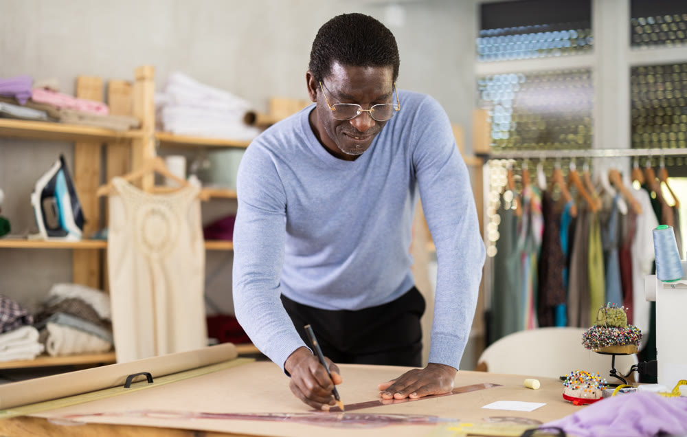 Experienced fashion designer drafting clothing pattern on paper in studio