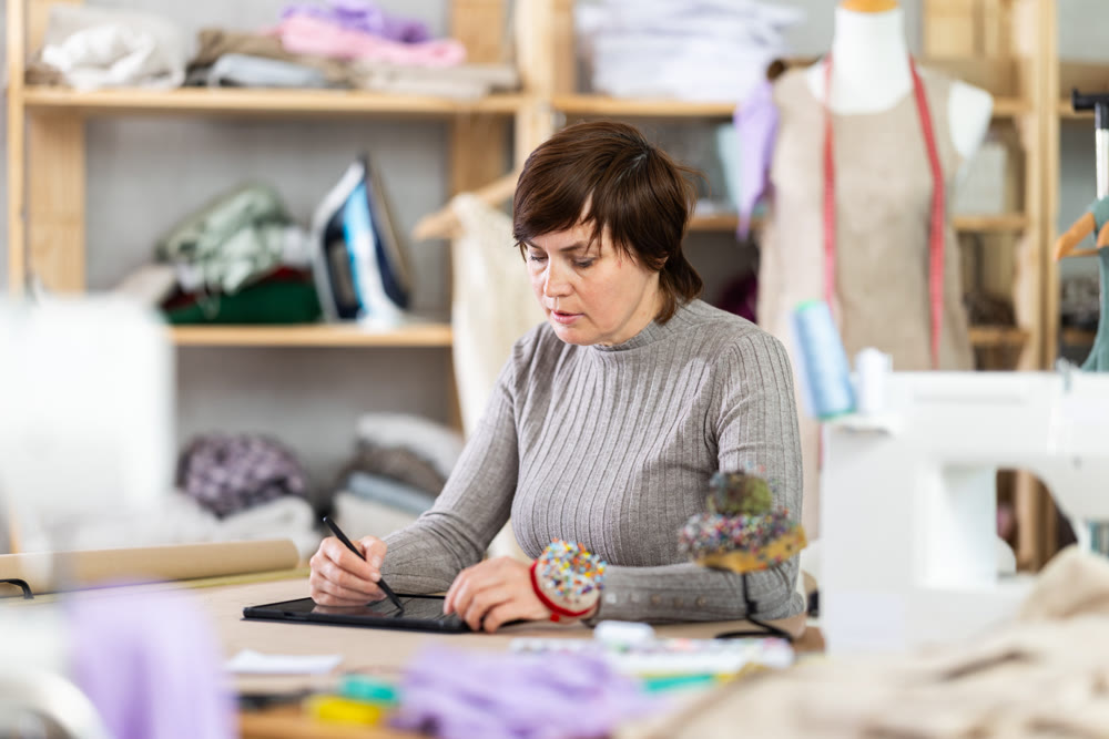 Woman tailor creates sketch of dress on tablet