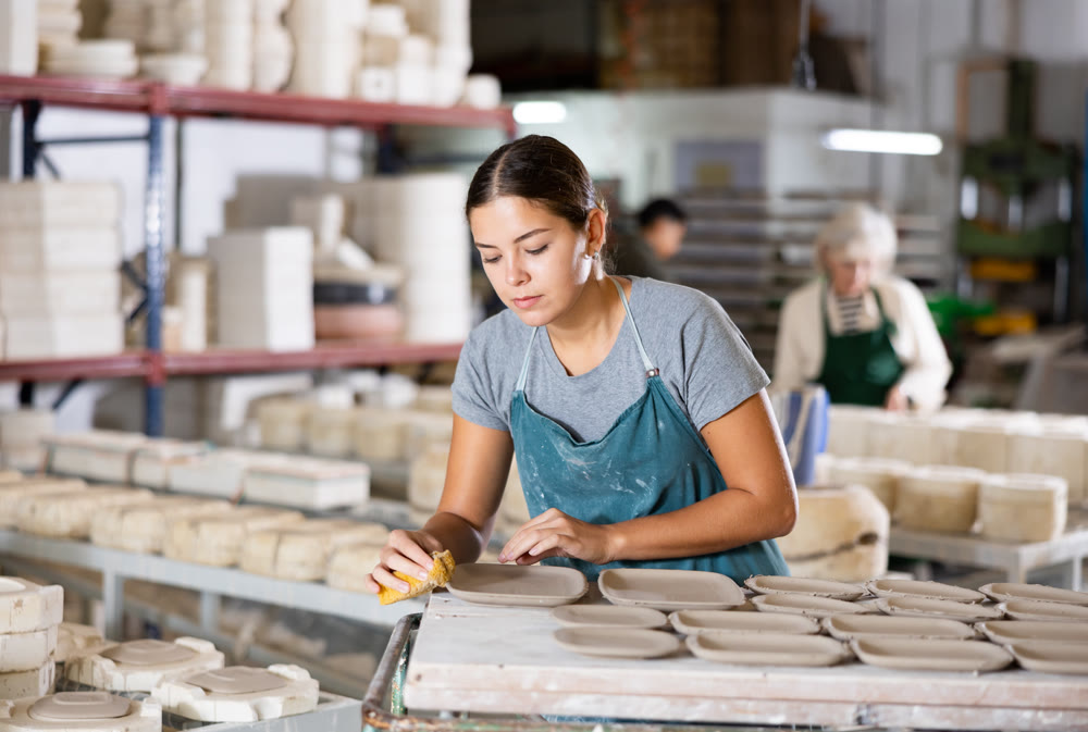 Woman potter polishing new crafted plates