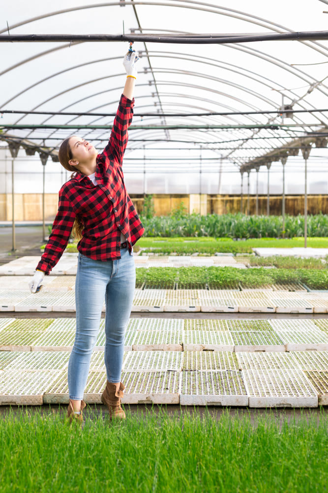 Hardworking young woman farmer opens a tap for watering