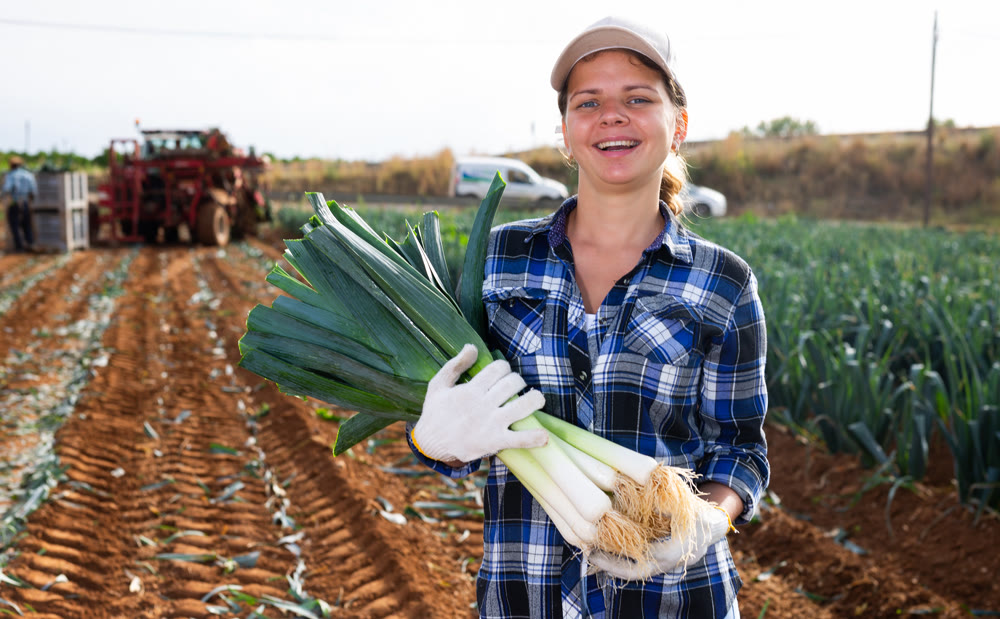 Woman posing with leek crop on field