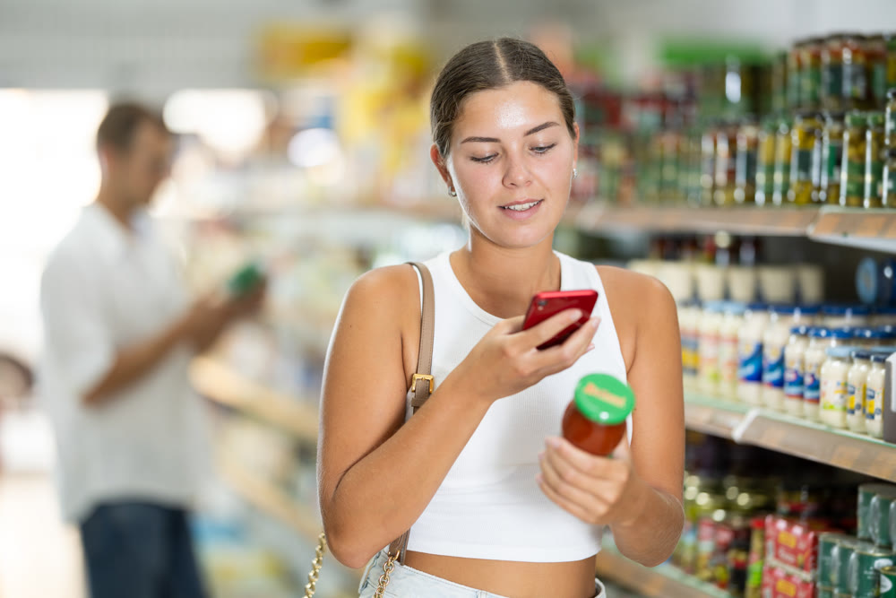 Girl buyer chooses red hot tomato sauce and scan QR code