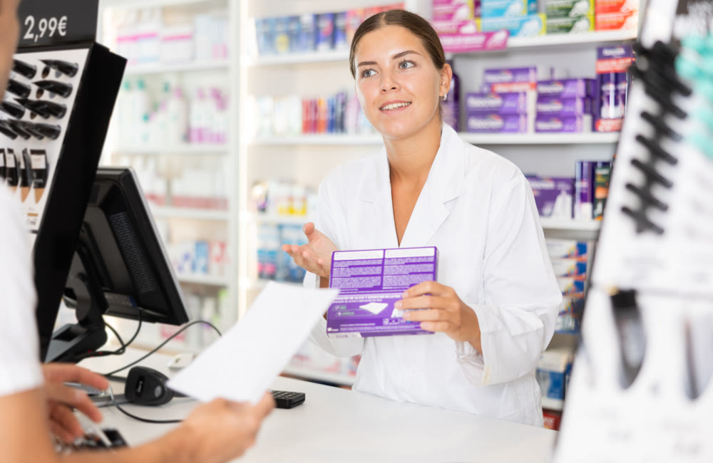 Girl pharmacist near cash register area serves customer, scans product and selling drugs