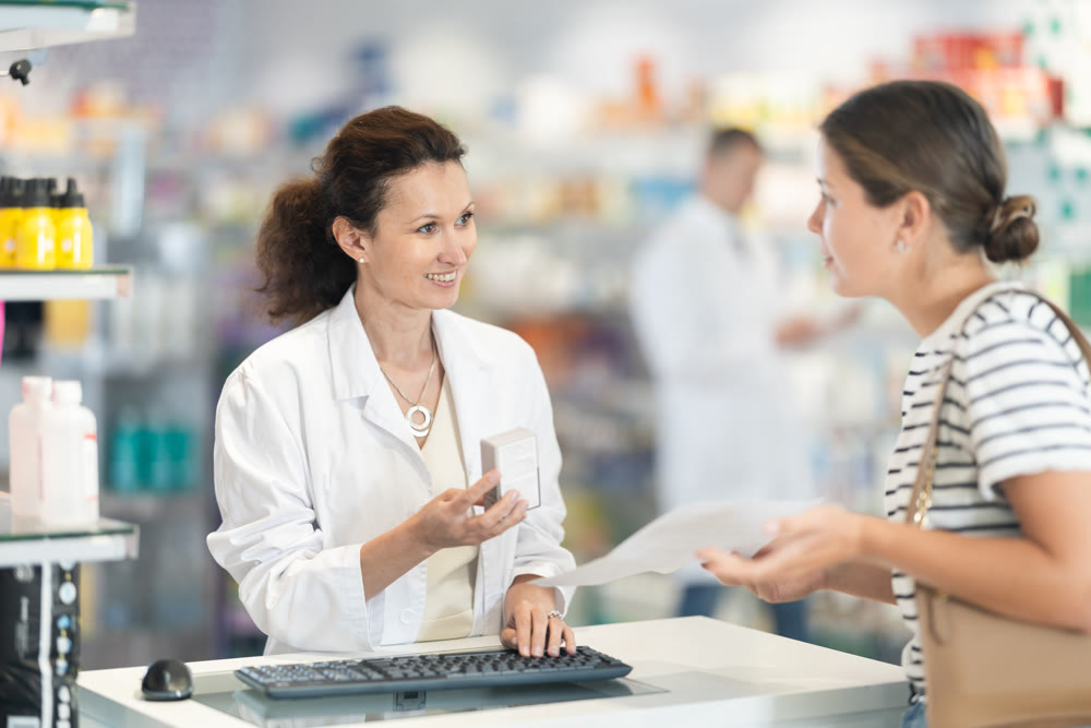 Female pharmacist offering medicine for sore throat to female customer