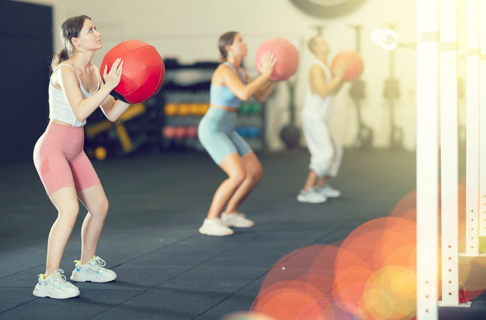 Athletic woman in sportswear training with ball in gym
