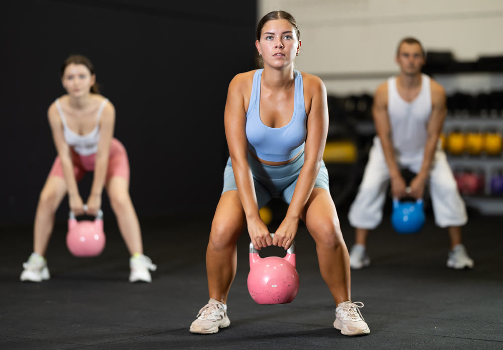 Sporty athletic woman in sportswear training with kettlebell in sport gym
