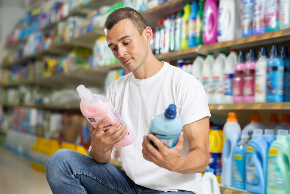 Man customer in store chooses package of laundry detergent