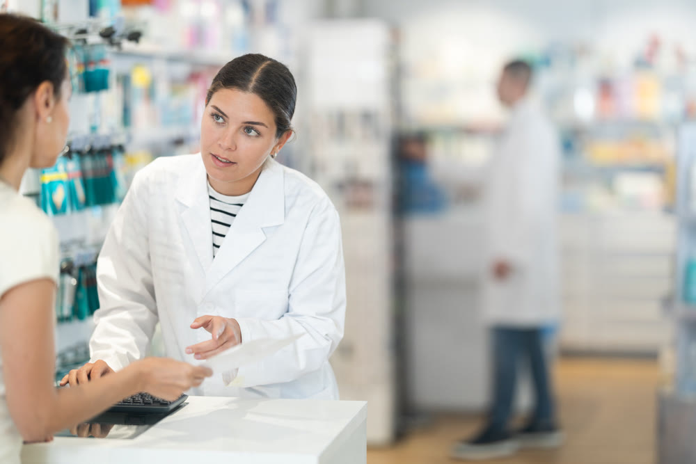 Young female pharmacist consulting woman client about medicine indicated in her recipe