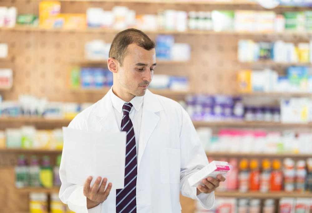 Male pharmacist with medical prescription in hands.