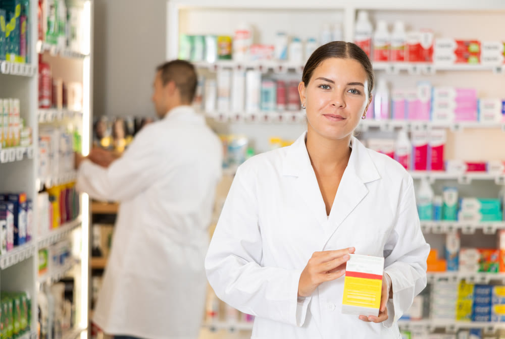 Female consultant pharmacist holds box in hands and offers to purchase remedy to alleviate condition