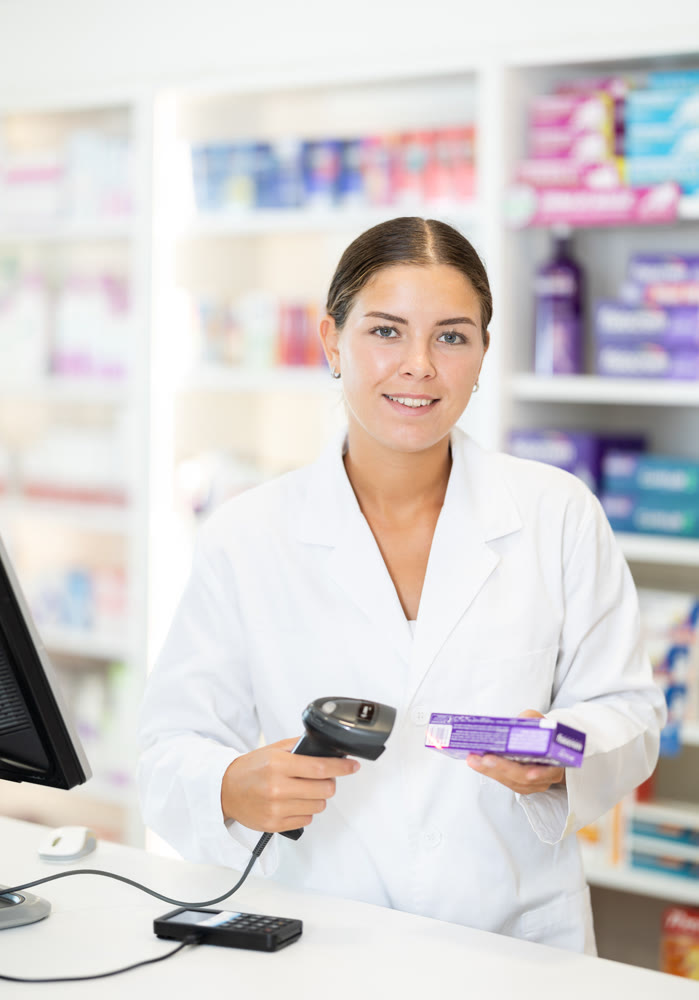 Young female pharmacist scanning barcode on sold medicine box