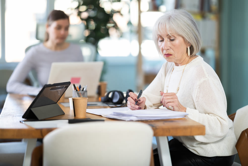 Senior woman working, fill in document in office