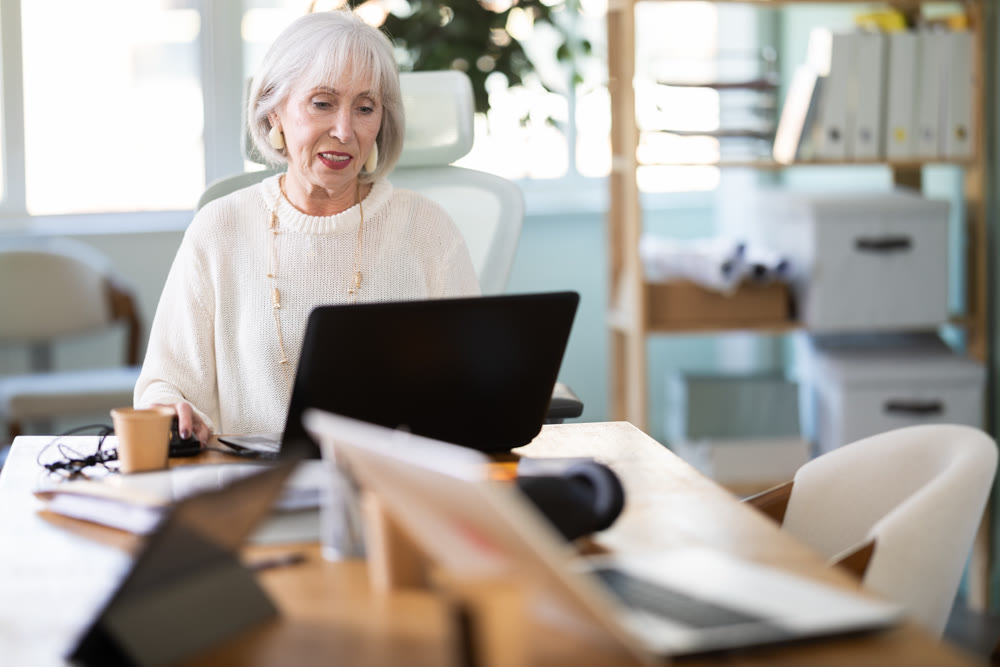 Elderly businesswoman, senior manager, work on laptop in modern company office