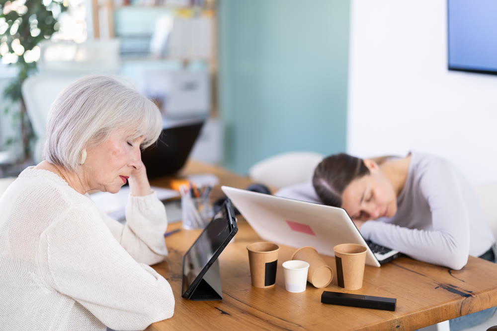 Tired elderly and adult female colleagues fall asleep while working