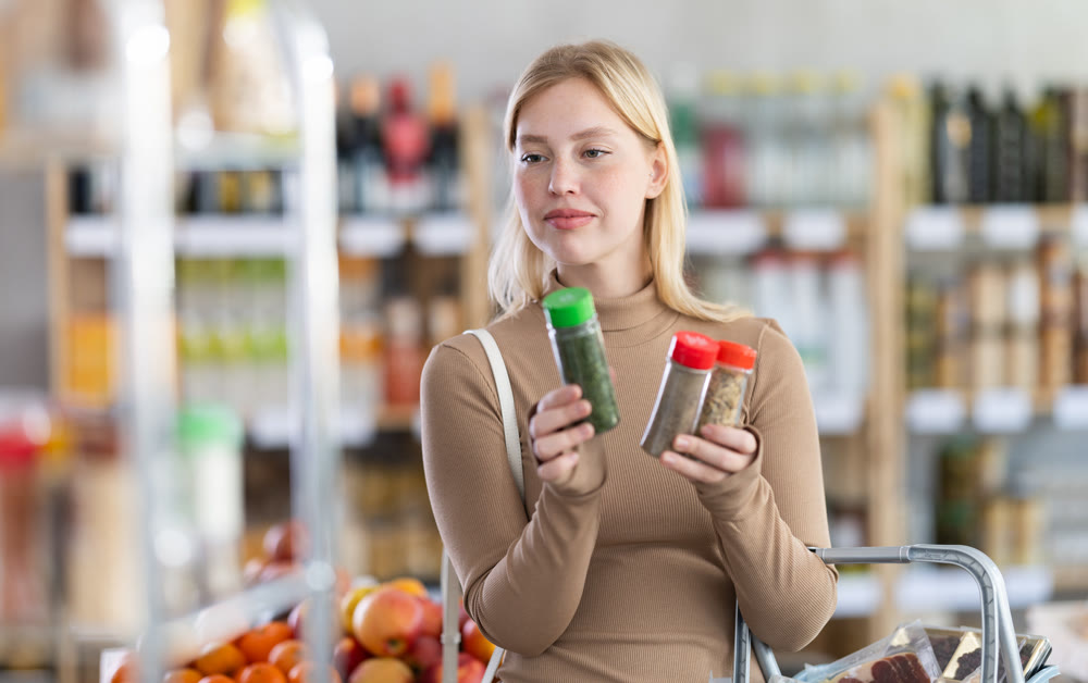 Young woman choosing spices and seasonings in grocery