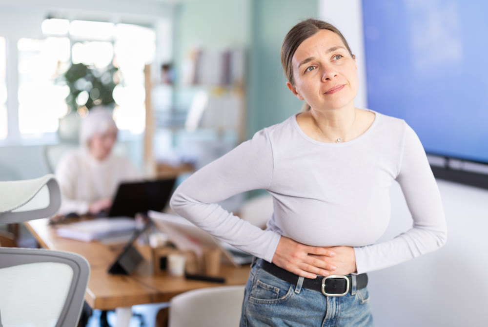 Adult woman with stomach pain during workday in office