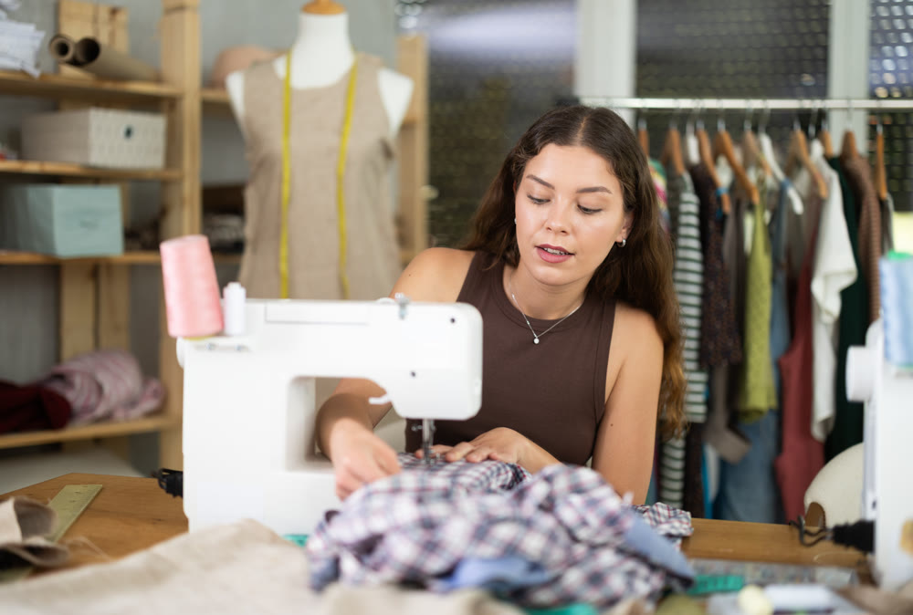 Female fashion designer sewing to order in the workshop