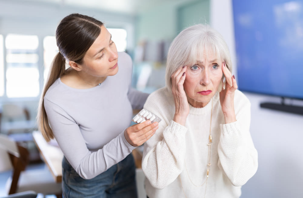 Elderly businesswoman suffers from a headache. Colleague offers her headache pills.
