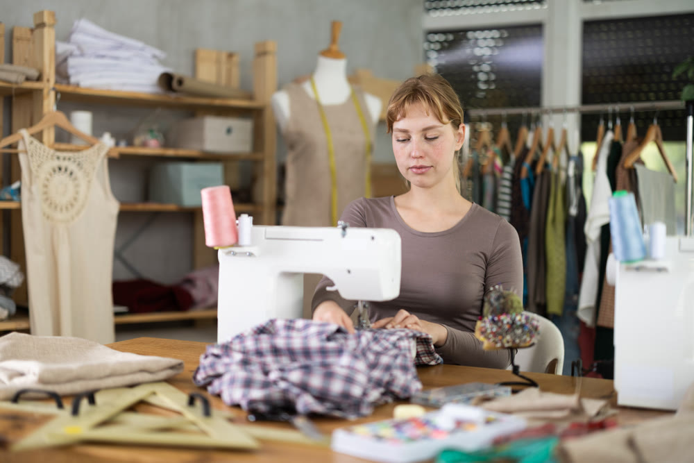 Female seamstress working on sewing machine in workshop