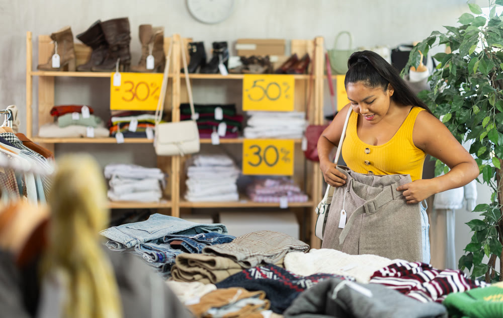 Young woman choosing trousers in clothing store