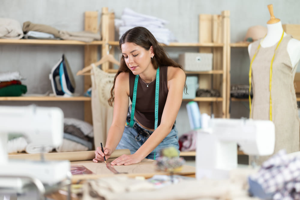 Woman tailor drawing on brown paper in workshop