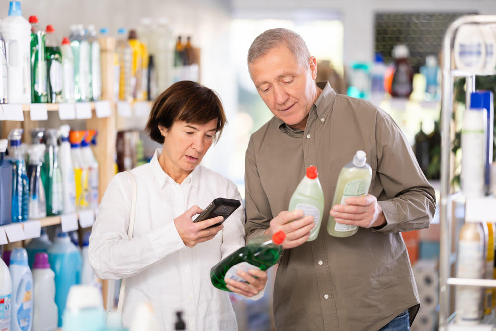woman scans the barcode and shows her elderly husband the price of household chemicals