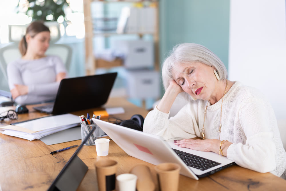 Tired women sleeps next to computer at work.