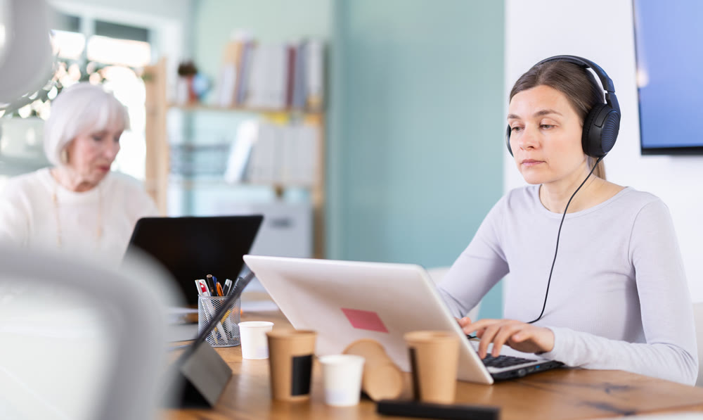 Woman working in office, using laptopat workplace.