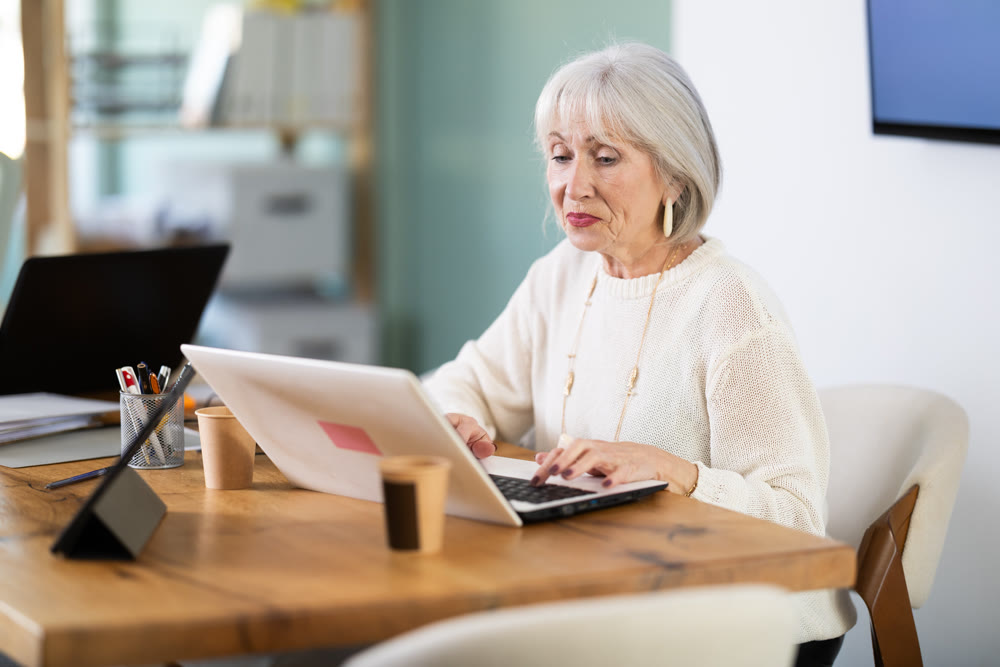 Elderly businesswoman, senior manager, work on laptop in modern company office