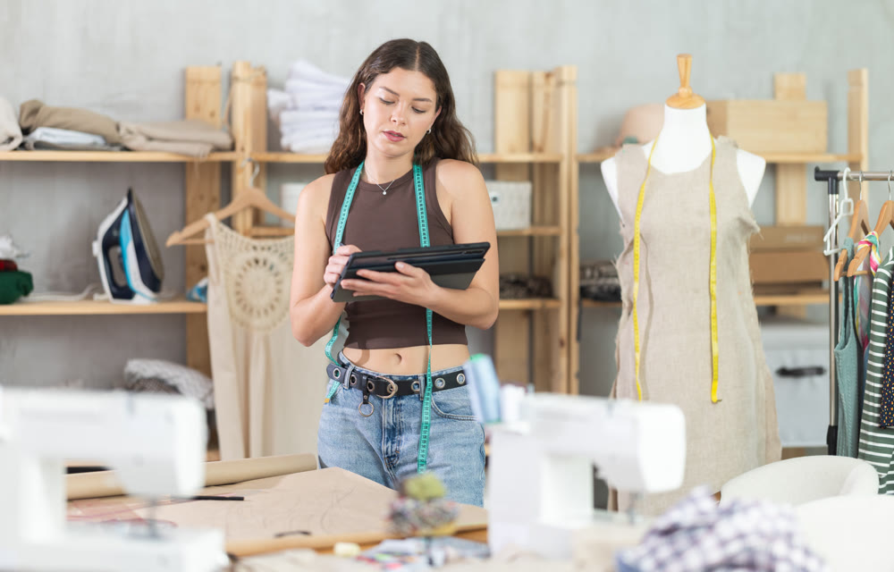 Tailor drawing fashion design on tablet in workshop