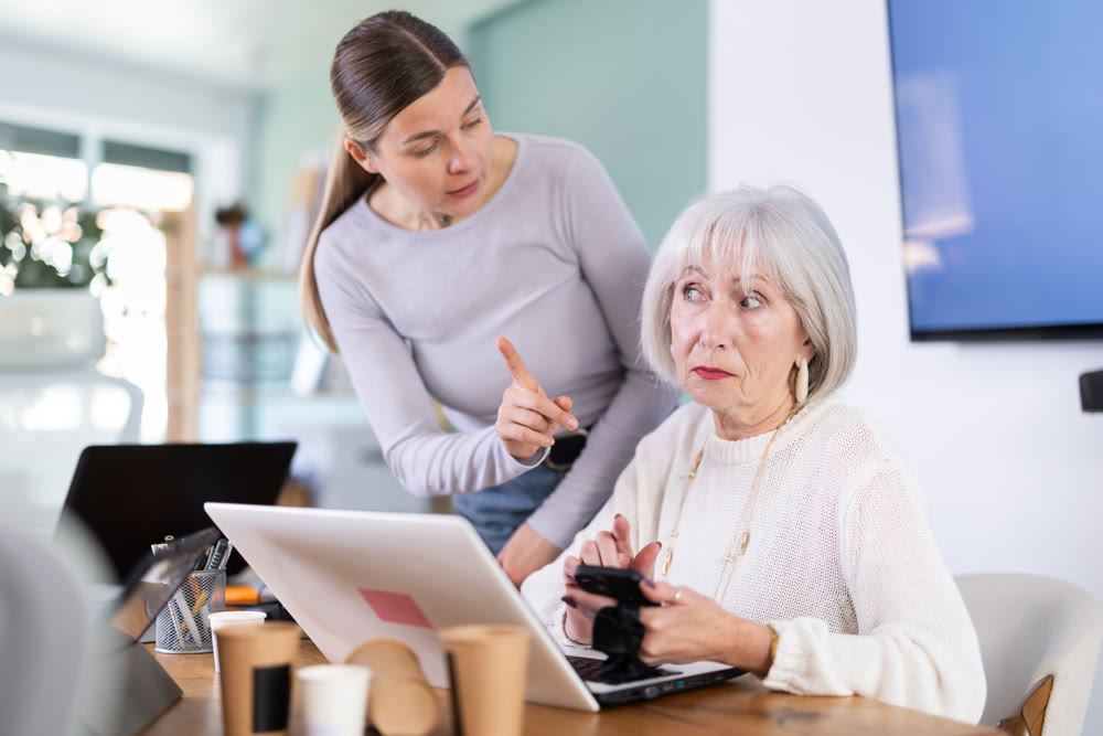 Businesswoman complains to mature employee about her talking on her mobile phone while working in office