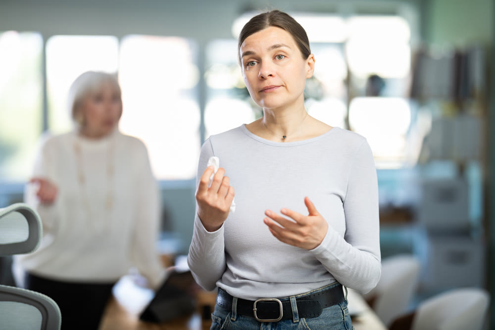 Sad woman staff stands in office