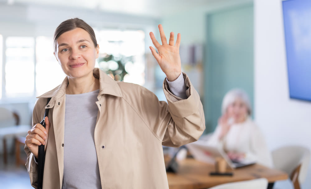 Adult woman leaving office saying goodbye to colleague