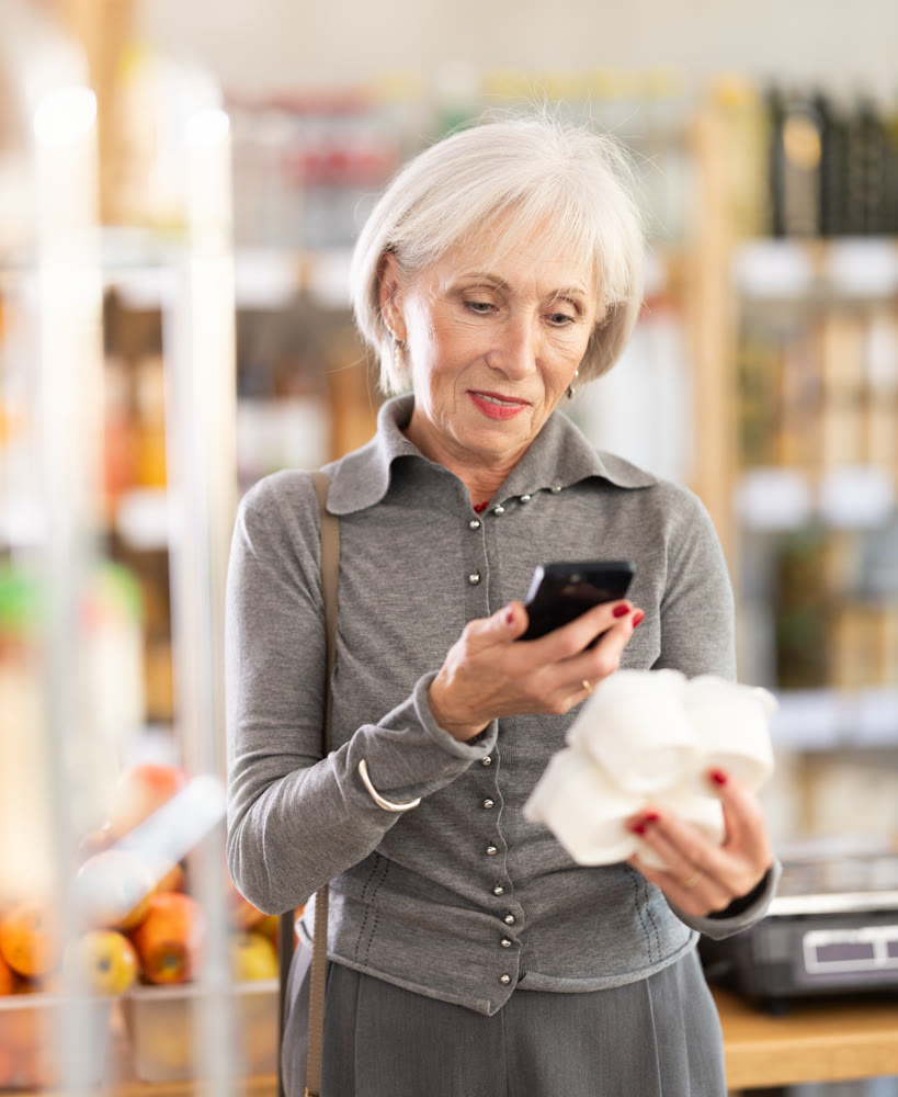 Elderly woman scanning qr code for yogurt